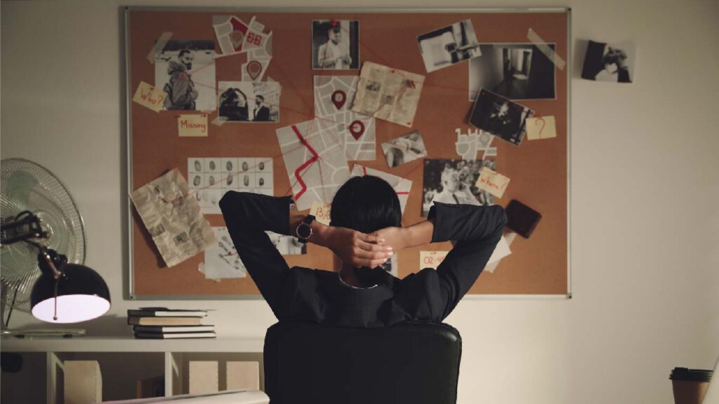 Detective looking at evidence board in office, back view